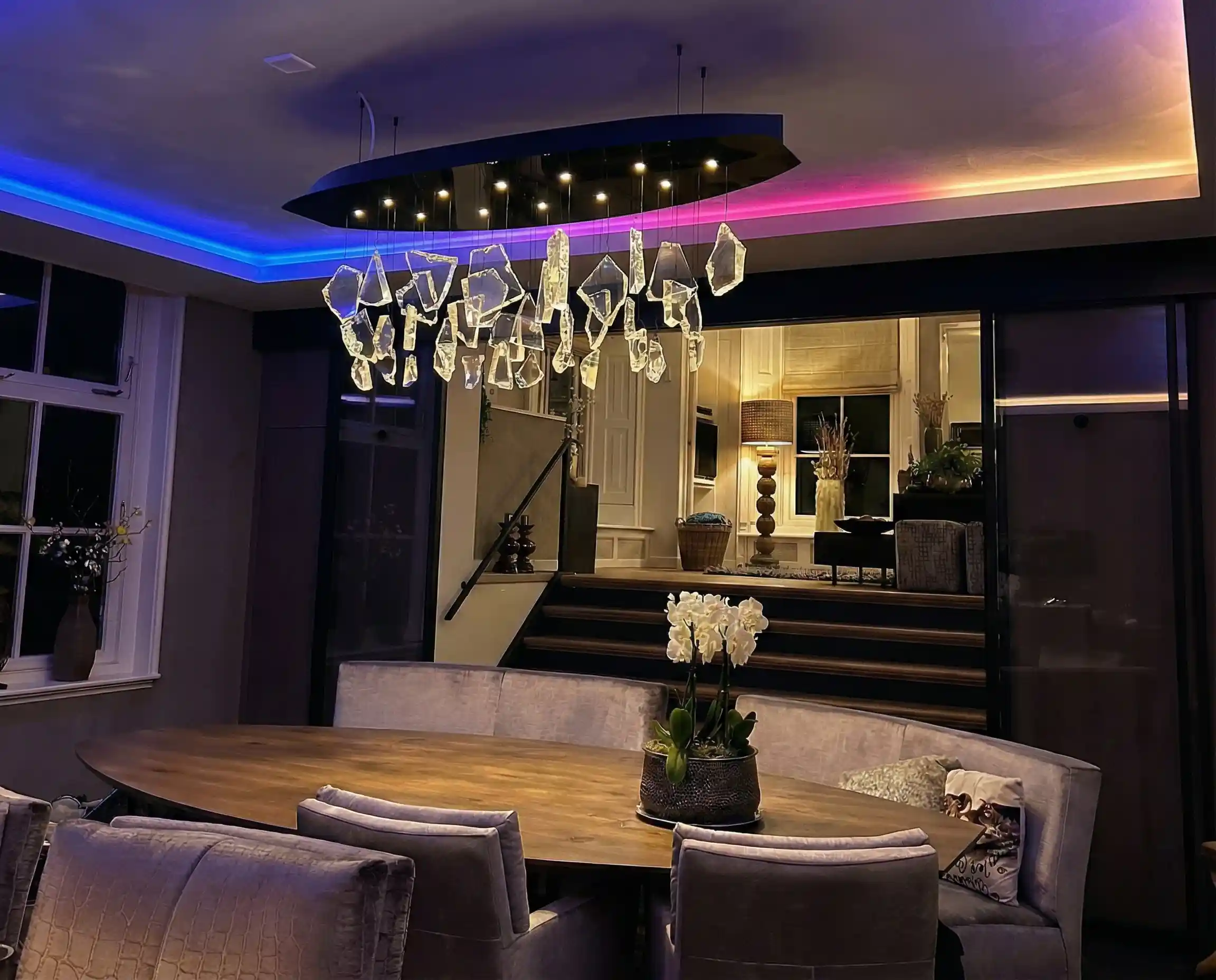 RGB LED-strip in koof zorgt voor sfeervolle gekleurde plafondverlichting in moderne eetkamer met luxe uitstraling.