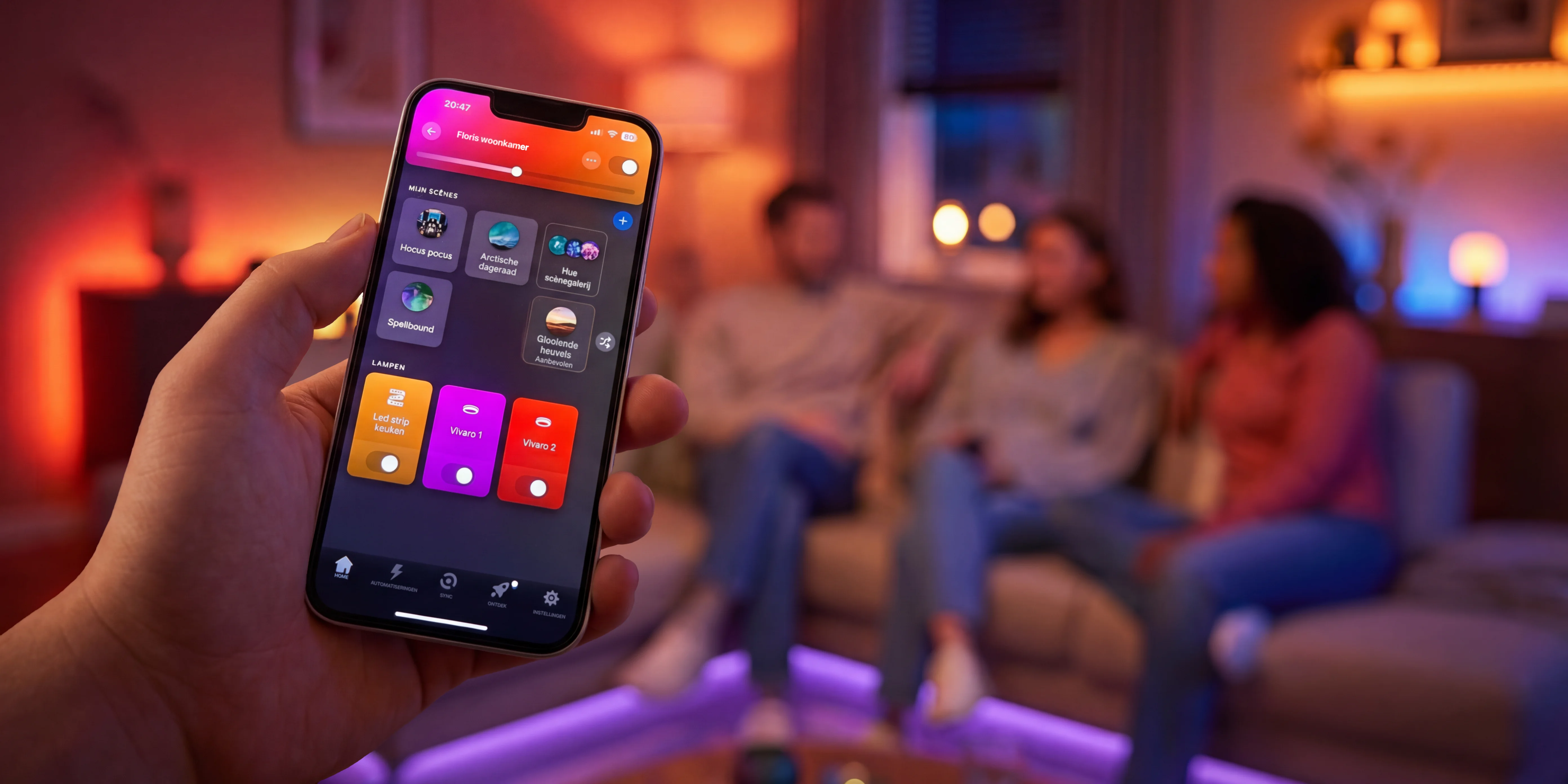 Smartphone met app voor het bedienen van LED-strip sfeerverlichting in een moderne woonkamer met vrienden op de bank